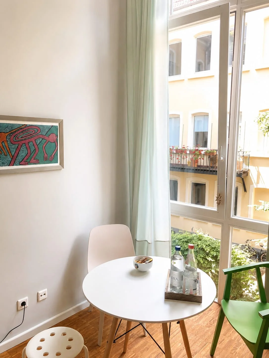 Helle Sitzecke am Fenster mit rundem Tisch und Blick in den begrünten Innenhof